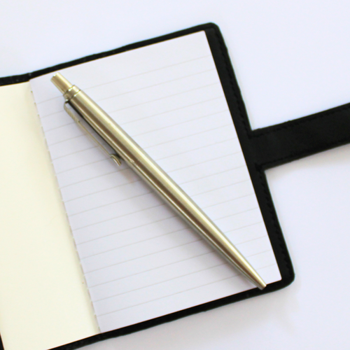 Black notebook cover inside view of lined paper with silver pen