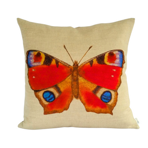 Peacock butterfly cushion in vibrant reds and blues against a neutral linen background