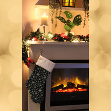 Load image into Gallery viewer, Snowflake Christmas stocking in green hanging from a mantlepiece
